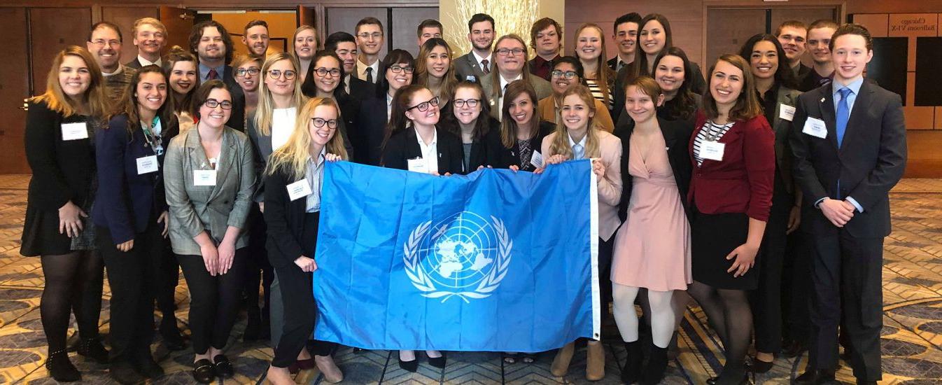 The Model UN team poses at a conference with their logo. 